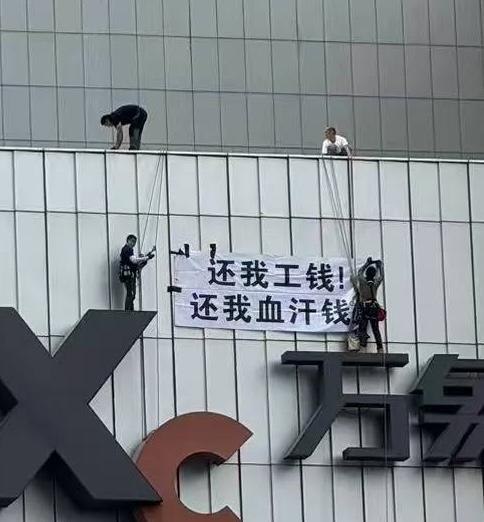 高空讨薪9月9日，央企华润集团旗下南京城北万象汇，几名讨薪工人通过绳索在万象汇外墙巨型logo上展示讨薪标语：还我工钱，还我血汗钱