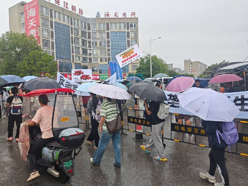 抗议现场，学生和商户冒雨举起横幅： 