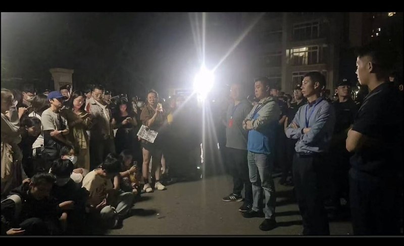 6月10日凌晨，重庆“山姆打包哥”虐狗事件抗议现场静坐抗议的市民对峙双手交叉的便衣警察