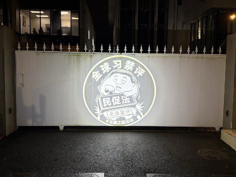 【中国行动·光覆之路｜“来抓我呀”全球系列行动第三站：新西兰·奥克兰】 7月7日晚，中国驻奥克兰领事馆外，光覆之路志愿者将“全球习禁评”的光延续到了新西兰起初，气喘吁吁的外交部安保人员，大脑空白，手足无措的站在投影前，足足数分钟后才开始用手遮挡志愿者的投影