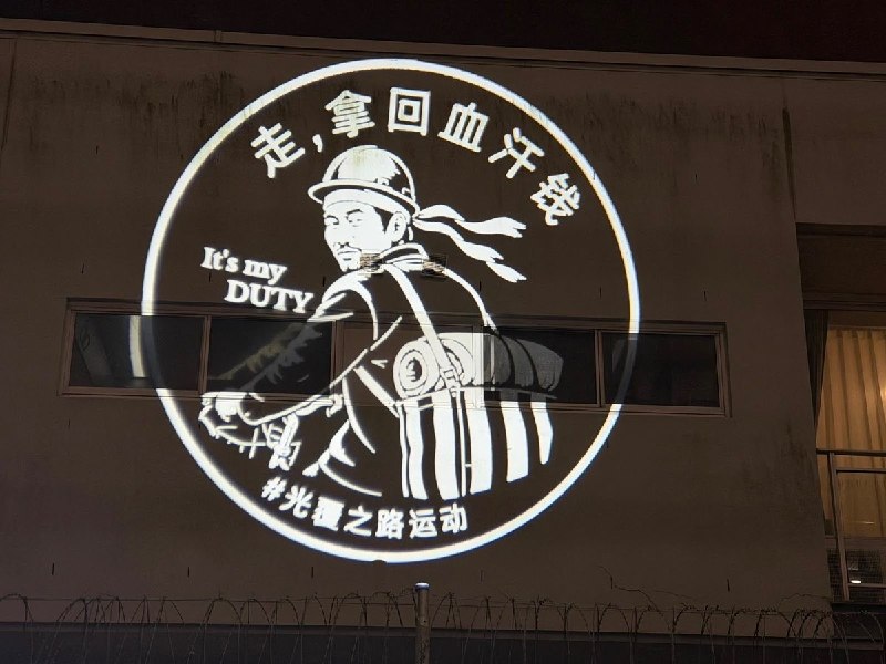 【中国行动 · 光覆之路运动 · 第五站｜悉尼】六月八日夜，中国行动志愿者在悉尼中国领事馆墙面上亮起了一名农民工的画面：安全帽、工装，扛着进城的行李，回头说