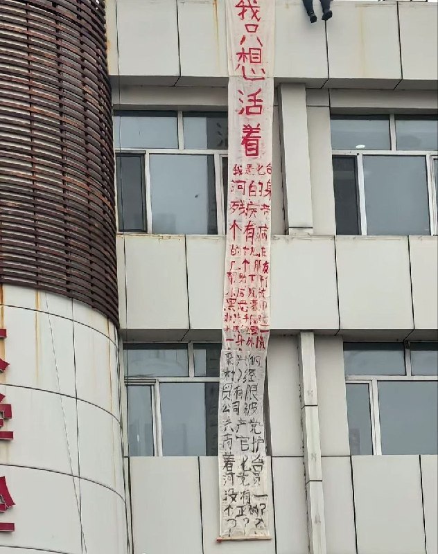 网友投稿:黑龙江省七台河市，一名男子坐在楼边拉横幅维权