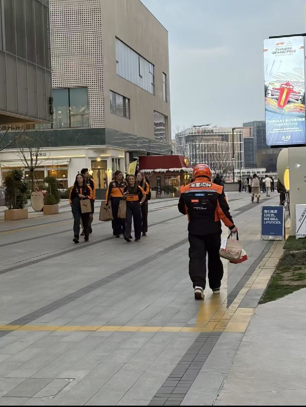 3月11日，上海，一名淘宝闪购外卖员和几名迈凯伦F1赛车手擦肩而过，相似的服装配色，却是截然不同的人生轨迹