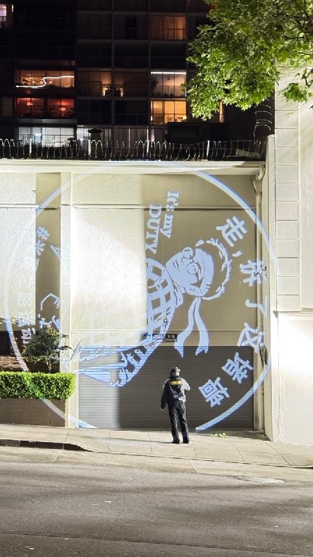 【中国行动 · 光覆之路运动 · 第四站｜旧金山】6月7日夜，旧金山中国总领事馆正面外墙，亮起一名程序员的画面：格子衫、抱着笔记本，回头说